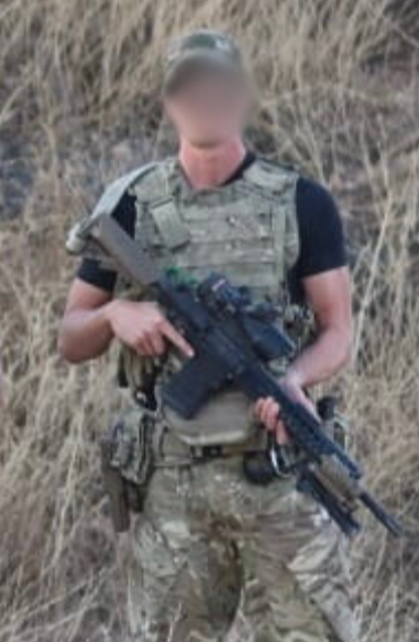 Person in military gear holding a rifle in a natural setting