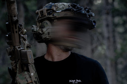 Person in camouflage gear holding a rifle in a forest setting