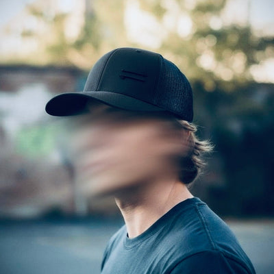 Person wearing a dark cap and shirt with a blurred background